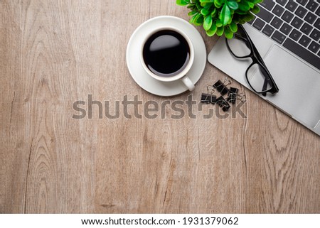 Flat lay, top view office table desk. Workspace with, laptop,office supplies, pencil, green leaf, and coffee cup on wood background.