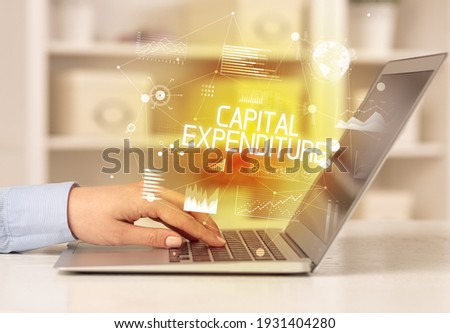 Side view of a business person working on laptop with CAPITAL EXPENDITURE inscription, modern business concept