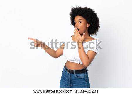 Young African American woman isolated on white background with surprise expression while pointing side