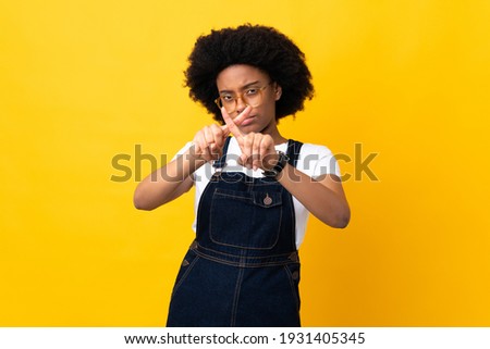 Young African American woman isolated on yellow background making stop gesture with her hand to stop an act