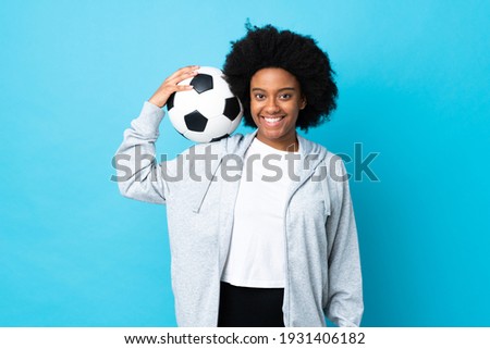 Young African American woman isolated on blue background with soccer ball