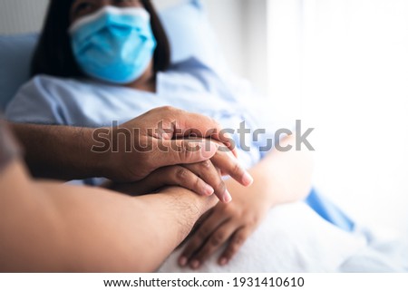 The people hold hands woman patient Which wearing a surgical mask and lying in the patient's bed, to encourage To fight the disease, cheer to receive treatment, to people and health care concept. Royalty-Free Stock Photo #1931410610