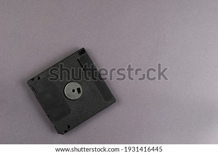 3.5 inches floppy disk on a gray background. Black plastic obsolete information carrier. Top view, flat lay. Copy space.