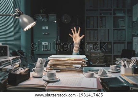 Desperate office worker overwhelmed with paperwork, she is asking help with her hand Royalty-Free Stock Photo #1931417465