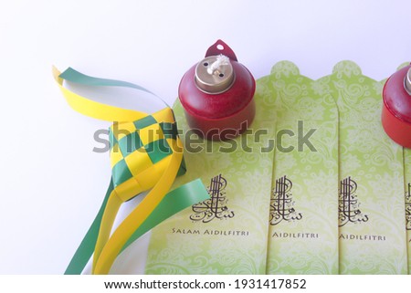 Selective focus of Ketupat (Rice Dumpling) with oil lamp or pelita and money packets isolated on white background with a blank for writing. Muslim celebration. Eid mubarak. Eid fitr