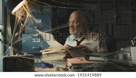 Corporate businessman searching for paperwork in an abandoned office: failure, financial crisis and outdated business concept Royalty-Free Stock Photo #1931419889