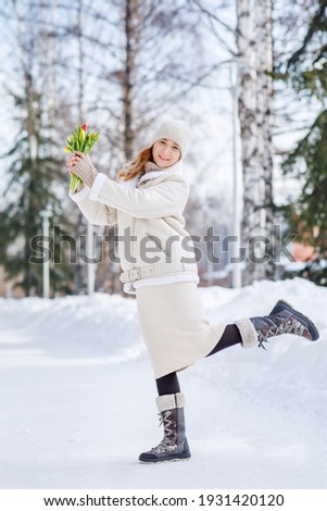 A girl with a bouquet of yellow and pink tulips on a walk on a sunny winter day. Flowers for International Women's Day. The nature of Siberia in Russia.
