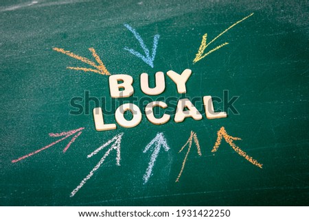 Buy Local. White wooden alphabet letters on a green chalk board.