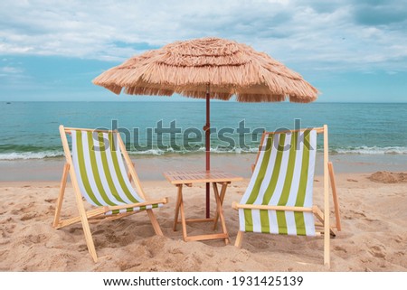 Straw beach rattan parasol with green beach chairs at the beach with blue sky backgrounds. Relaxing day at the beach