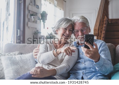 Smiling sincere mature older married family couple holding mobile video call conversation with friends, enjoying distant communication with grown children, using smartphone applications at home. Royalty-Free Stock Photo #1931428745