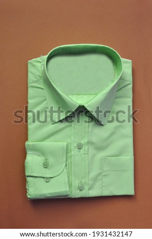 new fabric packed men's green shirt on a red brown background. Shirt packed for sale. Isolated shirt. Concept wear for bussiness