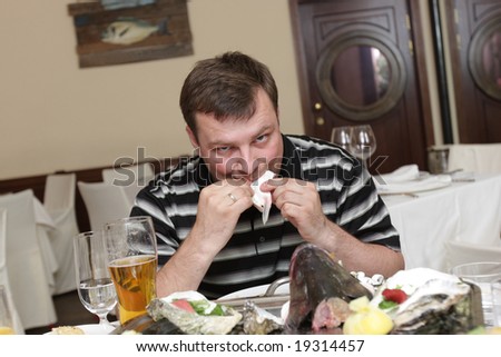 The man eats fish in seafood restaurant