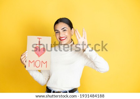 Beautiful woman celebrating mothers day holding poster love mom message doing hand symbol