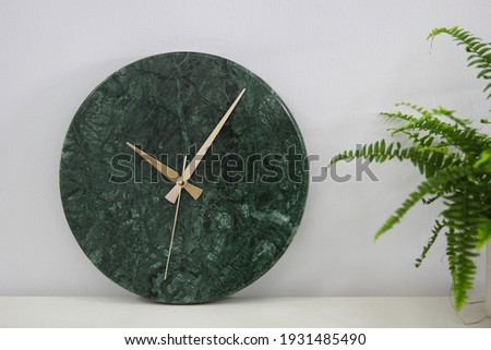 Decorative wall clock, green marble wall clock, natural granite stone , sophisticated and qualited, dark green clock, brass hour and minutes hand, clean background Royalty-Free Stock Photo #1931485490