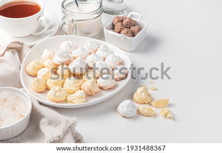 Lemon and white meringues on the background of a cup of tea and cane sugar. Side view with copy space.