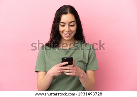 Young caucasian woman isolated on pink background sending a message or email with the mobile