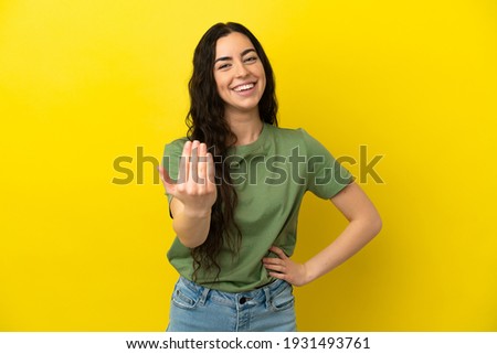 Young caucasian woman isolated on yellow background inviting to come with hand. Happy that you came Royalty-Free Stock Photo #1931493761
