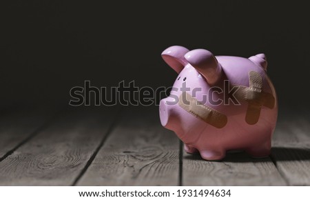 Broken piggy bank with band aid bandage or plaster finance background concept for economic recession or bankruptcy Royalty-Free Stock Photo #1931494634