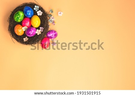 Colorful painted Easter Egg Nest with orange pastel colored background top view, Happy Easter Holliday concept background with Copy space spring bright colors design space for text