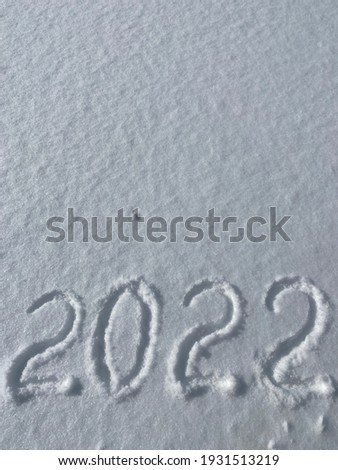 Inscription 2022 on the snow with copy space. Natural texture for New Year's design.