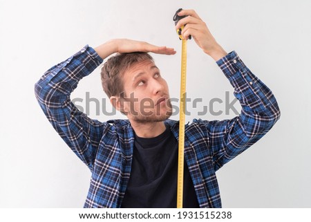 simple adult teenager male person with a roll tape measure the height against the wall Royalty-Free Stock Photo #1931515238
