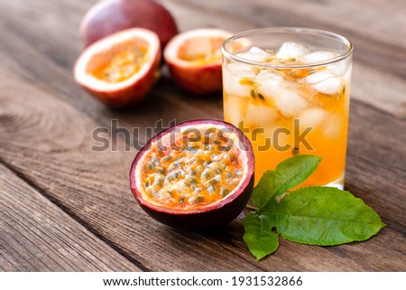 Passionfruit juice in glass and fresh passion fruit with green leaf isolated on wooden table background.  Royalty-Free Stock Photo #1931532866