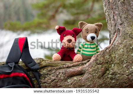Amigurumi doll cat and dog with a backpack in the forest.