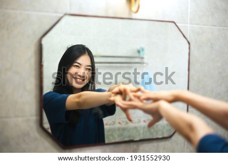 Young adult smile asian woman practice self talk conversation with mirror. Mental health in bathroom at home. Healthy lifestyle after wake up life with satisfaction concept. Royalty-Free Stock Photo #1931552930
