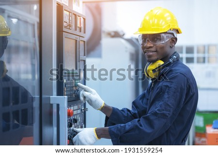 Black man working at programmable machine in factory industries  Royalty-Free Stock Photo #1931559254