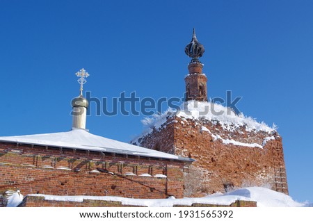collapsing brick towers of an old orthodox Church of St. Nicholas the Wonderworker in Gnezdilovo covered with ice and snow on a winter day against a blue sky
