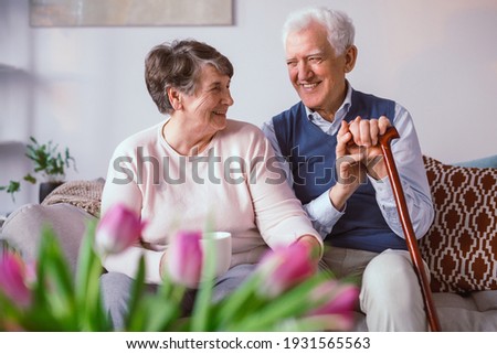 Senior happy couple sitting together on a couch in a nursing home Royalty-Free Stock Photo #1931565563