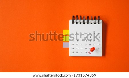 red thumbtacks pointed at the end of month on white calendar  with vivid grunge orange paper background , business or education concept Royalty-Free Stock Photo #1931574359