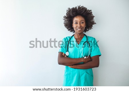Healthcare, profession, people and medicine concept - Happy doctor or nurse at hospital corridor. Covid-19, coronavirus disease, healthcare workers concept. Professional good-looking African doctor