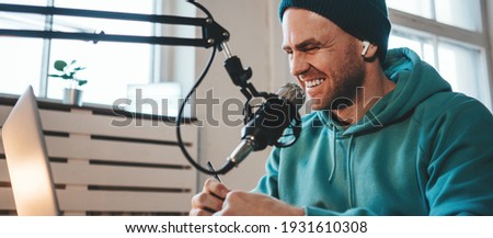 A host streaming his live podcast using microphone and laptop at his homemade broadcast studio