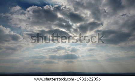 Sun rays bursting through clouds Royalty-Free Stock Photo #1931622056