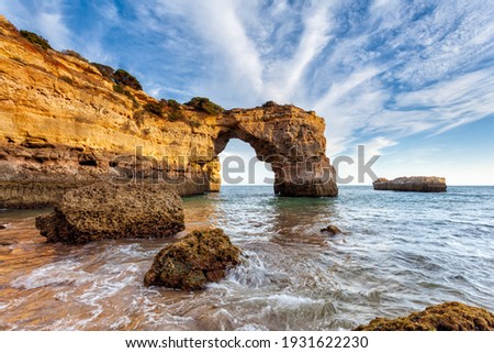 Amazing beach at sunrise. Algarve is located in the south of Portugal and is a vacation destination for many tourists. Your stone arch is an excellent spot for photographers and spearfishing Royalty-Free Stock Photo #1931622230