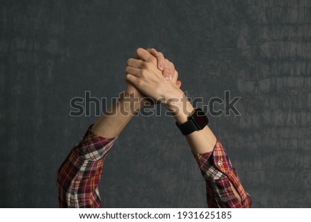 Hands of a man in a shirt with an electronic watch on a dark background