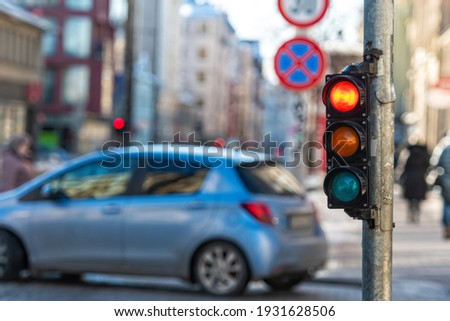 close-up of small traffic semaphore with red light against the backdrop of the city traffic