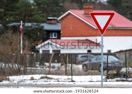 road sign GIVE WAY against the background of a defocused residential area, close-up