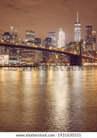 Brooklyn Bridge and New York City skyline at night, color toning applied, USA.