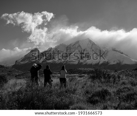 People in front of the mountains in Patagonia, taking photos. 