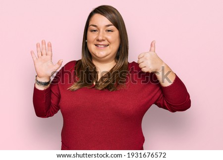 Beautiful brunette plus size woman wearing casual clothes showing and pointing up with fingers number six while smiling confident and happy. 