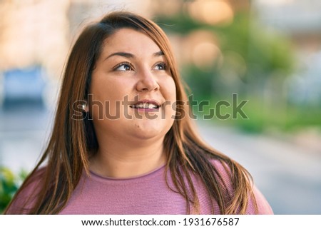 Young hispanic plus size woman smiling happy standing at the park.
