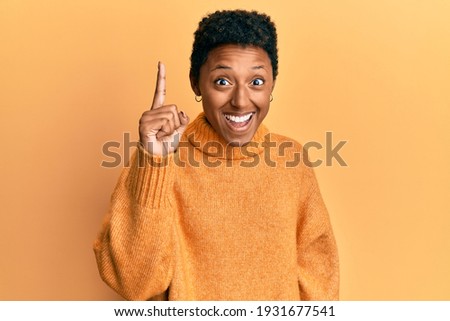 Young african american girl wearing casual clothes pointing finger up with successful idea. exited and happy. number one. 