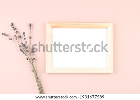 Wooden photo frame with white blank card and flowers on pastel pink background. Mock up poster frame. Stylish template. High quality photo
