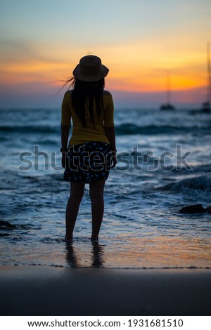 A woman standing and watching the sunset on the beach