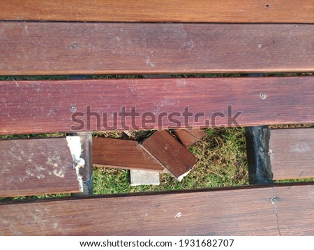 Garden bench made of artificial wood panels in brown, broken into small pieces.