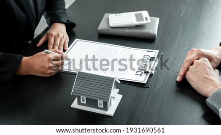 Real estate agent working sign agreement document contract for home loan insurance approving purchases for client with house model and key on table.