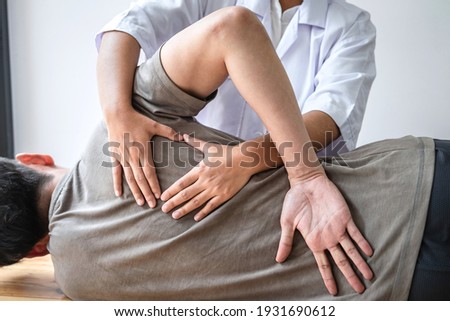 Doctor or Physiotherapist working examining treating injured back of athlete male patient, Doing the Rehabilitation therapy pain in clinic. Royalty-Free Stock Photo #1931690612
