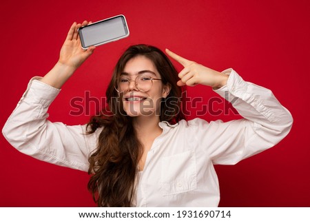 Photo of beautiful smiling young woman good looking wearing casual stylish outfit standing isolated on background with copy space holding smartphone showing phone in hand with empty screen display for